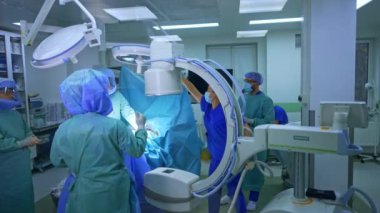 C-Arm X-ray makinesi ameliyat masasının yanındaki ameliyathanede. Tıbbi personel ortopedik operasyon için ekipman ayarlar. Modern operasyonel tiyatronun kapısındaki pencereden bak..