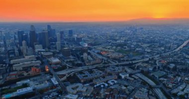 Şehrin puslu mavi panoramasının üzerinde parlak turuncu gökyüzü. Los Angeles, California, ABD 'nin alacakaranlıktaki hava manzarası.