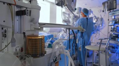 Modern akciğer havalandırma makinesi ameliyatta çalışıyor. Üniformalı erkek cerrah geleceğin Da Vinci robotunun ameliyatında duruyor..