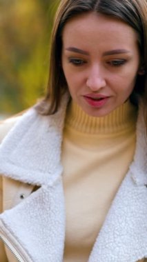 Modern genç kadın doğada otururken dizüstü bilgisayar kullanıyor. Masada oturmuş bilgisayar ekranına bakan esmer güzel bayan. Sonbahar doğa arka planı. Dikey video