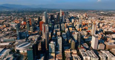 Los Angeles, Kaliforniya 'nın iş merkezindeki gökdelenlere yaklaşıyoruz. Metropolis 'in üstündeki insansız hava aracı görüntüleri. Arka planda kayaların sisli siluetleri. Hava görünümü.