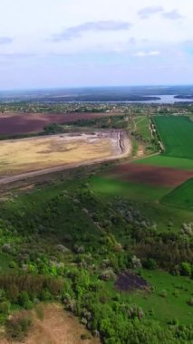 Büyük bir şehrin dışındaki güzel, çeşitli doğal manzara. Bulutlar yere gölge düşürüyor. Yukarıdan bak. Dikey video