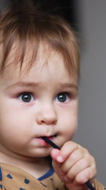 Kordonla oynayan komik, sevimli bir çocuk. Dişler uzadığında bir şeyleri ağzına iten bir çocuğun portresini yakından çek. Dikey video