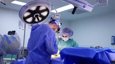 Kadın hemşirenin yardımıyla erkek cerrah tarafından yapılan beyin cerrahisi. Cerrahi hoparlörlerdeki doktor çalışmalarında modern tıbbi aletler kullanıyor..