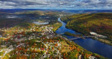 Nehir ve dağların yakınındaki yerleşim yerinin muhteşem manzarası. Sonbaharda Vermont, New England, ABD 'nin panoramasına hava perspektifi. Gökyüzünde dramatik bulutlar.