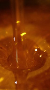 Kehribar balı tabağa akıyor. Temizlik için metal eleğe dökülen güzel taze organik ürün. Dikey video