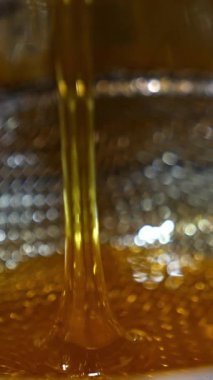 Metal eleğe akan küçük bal akıntısı. Kapatın. Çerçevelerden çıkarıldıktan sonra organik bal filtreleme. Dikey video