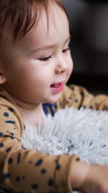 Aktif beyaz çocuk yumuşak bir yastığın üzerinde onunla neşeyle oynuyor. Sevimli çocuk merdivenleri çıkmak için ayağa kalkar. Kapatın. Dikey video