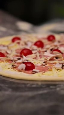Pizzacı pizza yapıyor. Şef pizza spatulasını kullanarak pizzayı fırına veriyor. Gıda hazırlama konsepti Dikey video