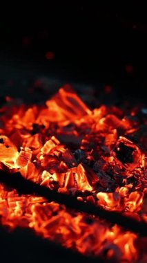 Kamp ateşinde odun yakmak. Yanan siyah ahşap üzerinde detaylı ateş hareketi. Parlak alevlerin içindeki tahta kütükler. Dikey videoyu kapat
