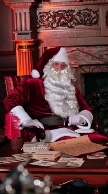 Güzel eski mobilyaları ve şöminesi olan Noel Baba 'nın işyeri. Noel Baba kamarasının önünden bir şey düşünerek geçer. Dikey video