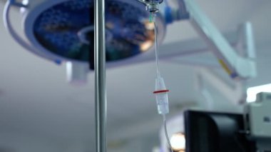 Damlayan bir ilaç ve damlayan bir damla sayacı ile ayakta durun. Kapatın. Bulanık arkaplanda, tavanda yuvarlak lamba..