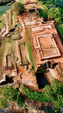 İnsanlar Sri Lanka 'daki antik Sigirya Kalesi' nin yıkıntılarının yanından geçiyor. Drone dağın tepesinden yükseliyor. Dikey video.