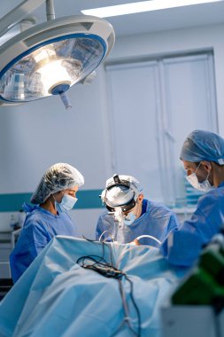 Cerrahlar hassas ameliyatları aydınlık odada yaparlar. Cerrahlardan oluşan bir ekip gündüz saatlerinde iyi aydınlatılmış bir ameliyathanede kritik bir cerrahi prosedüre odaklanır..