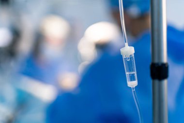 Tıbbi ekip ameliyathanede. Bir tıbbi ekip bir ameliyathanede gayretli bir şekilde çalışırken damar içi damlalar kritik bir sağlık durumunu ön plana çıkarıyor..