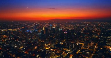 Los Angeles, Kaliforniya 'nın uçsuz bucaksız gece manzarası. Arka planda parlak turuncu gökyüzü. Hava perspektifi.