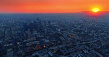 Alacakaranlık vakti ABD 'nin Los Angeles, Kaliforniya şehrinin engin mavi manzarası. Göz kamaştırıcı turuncu gökyüzü ve arka planda dağın arkasında güneş batıyor. Hava perspektifi.