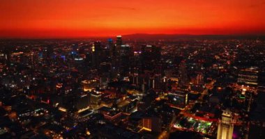 Los Angeles alacakaranlıkta ışıkları açtı. Tepesinde neon ışığı olan gökdelenler. Arka planda sıcak kırmızı gökyüzü. Hava perspektifi.