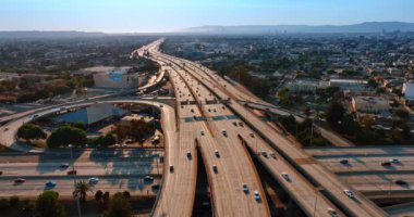 Birden fazla arabanın geçtiği güneşli otoyollar. Los Angeles, California, ABD 'de trafik çok hareketli. Hava görünümü.