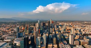 Uçsuz bucaksız şehrin manzarasında mavi gökyüzünde asılı şaşırtıcı beyaz bulutlar. Gündüz vakti Los Angeles, Kaliforniya, ABD 'de hava perspektifi. Arka planda puslu dağlar.