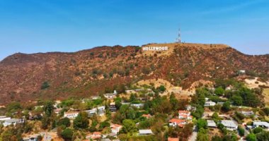 Hollywood yazısıyla Mount Lee 'den uzaklaşmak. İnsansız hava aracı yeşil alanın üzerinde uçuyor ve tepelerde lüks kulübeleri var. Los Angeles, Kaliforniya, ABD.