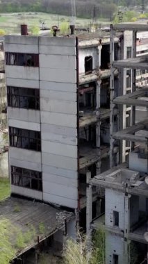 Hasarlı endüstri. Bir fabrikanın tamamlanmamış eski binaları olan terk edilmiş bir yer. İlkbaharda eski endüstriyel fabrika. İHA görüntüsü. Dikey video