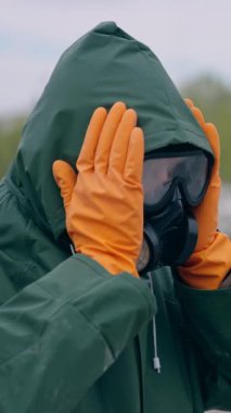 Kimyasal koruma giysisi giyen adam. Güvenlik üniformalı ve gaz maskeli bir insan terk edilmiş bir yerde duruyor. Biyolojik saldırı. Dikey video