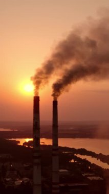 Endüstriden gelen tehlikeli dumanlar havayı kirletiyor. Gün batımında nehir kenarında sigara içilen zararlı bir fabrika. Küresel ısınma Çevre kirliliği. Dikey video