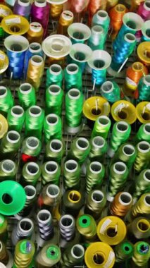 Renkli dikiş iplikleri arka planda. Birçok farklı renk ipliği makarası. Dikiş aletleri. Hobiler ve el sanatları. Dikey video