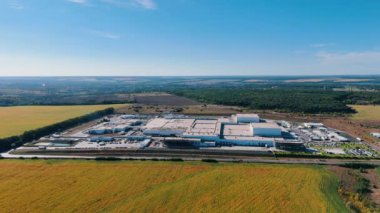 Tarımsal alanlarda yer alan modern bir endüstriyel girişimin geniş bir bölgesi. Güneşli bir günde fabrikaya yaklaşan İHA görüntüleri..