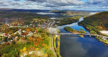Köprüler dağın eteklerinden nehri geçer. Sonbaharda Amerika 'nın New England şehrinin renkli Vermont manzarası. Arka planda bulutlu bir gökyüzü. Hava görünümü.