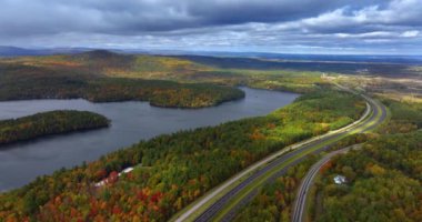 Modern otoyolların kesiştiği doğa manzarası. Gri bulutlar göl ve ormanlık alanların üzerindeki gökyüzünü kaplıyor. New York 'un kuzeyinde sonbahar. Hava görünümü.