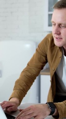 Genç adam çevrimiçi konuşuyor. Dizüstü bilgisayarın önünde müşterilerle çalışan serbest çalışan bir erkek. Öğrenci evde otururken bir video görüşmesi yapıyor. Uzak bir iş. Dikey video