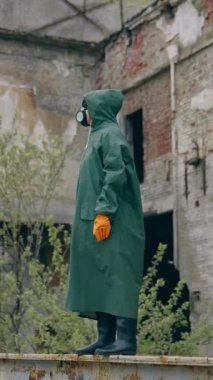 Koruyucu kimyasal giysinin içinde hayatta kalan biri. Virüslü bölgede, yıkılmış bir binanın arka planında tek başına duran kişi. Hava kirliliği. Dikey video