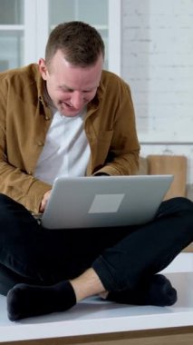 Genç adam internette uzun saatler çalışırken deli gibi görünüyor. Mutfak masasında oturan ve kablosuz bilgisayarda yazan bir adam. Evde bilgisayar oyunu oynayan komik bir adam. Dikey video