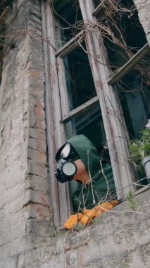 Kırık camları olan harap bir binadan insan solunum cihazına bakıyor. Biyolojik saldırıdan sonra terk edilmiş yerde saksı ve ekolojist. Dikey video