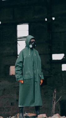 Mahvolmuş bina geçmişiyle ilgili güvenlik kıyafetli bir ekolojist. Gaz maskesi ve koruyucu giysiler giyen kişi, kimyasal saldırıdan sonra tehlikeli bir yerde duruyor. Dikey video
