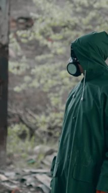 Mahvolmuş özel takım elbiseli bir adam. Yıkılmış bir yerde kimyasal koruyucu giysili bir insan. Kıyamet sonrası dünya konsepti. Terk edilmiş bir yerin gerçek arka planı. Dikey video
