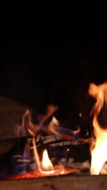 Taş şöminede yanan ahşap. Şömine yanıyor. Geceleri ısınmak için taş şöminede parlayan ateş. Kış tatilinde şöminenin yanında sıcak bir akşam. Dikey video