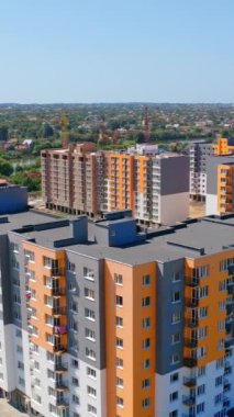 Yüksek binaları olan yeni bir yerleşim yeri. Renkli duvarları olan modern çok katlı binalar. Gün ışığında yeni yerleşim alanının inşaatı. Dikey video