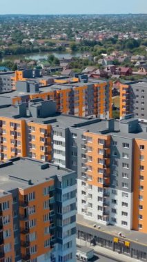 Çok katlı binaları olan bir yerleşim yeri. Şehrin eteklerinde yeni gökdelenleri olan modern bir bölge. Şehir konutlarının renkli mimarisi. Hava görüntüsü. Dikey video
