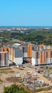 Kentsel arka planda yeni konut daireleri. Yeni şehir bölgesinde yüksek binaları olan bir yerleşim yeri. Hava görüntüsü. Dikey video