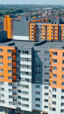 Modern bir apartmanın ön cephesi. Balkonları ve pencereleri olan çok katlı yeni bir binanın renkli duvarları. Güneşli bir günde yüksek konut binası. Dikey video