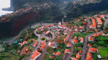 Portekiz, Madeira 'daki yerleşim alanının göz kamaştırıcı manzarası. Dağların arasında turuncu çatıları olan rahat bir şehir. Hava perspektifi.