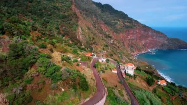 Yamaçlarda evleri olan inanılmaz dağlar. Kayaların dibindeki Atlantik Okyanusu 'nun masmavi suları. Madeira, Portekiz. Hava perspektifi.