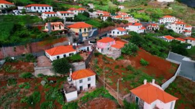 Kayalık arazide turuncu çatıları olan çok sayıda kulübe. Portekiz, Madeira 'daki yerleşim alanının üstündeki İHA görüntüleri.