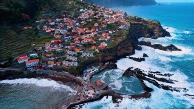 Portekiz 'in Madeira kayalık kıyısındaki yerleşim yerinin muhteşem manzarası. Atlantik Okyanusu 'nun dalgaları kayalara çarpıyor. Hava perspektifi.