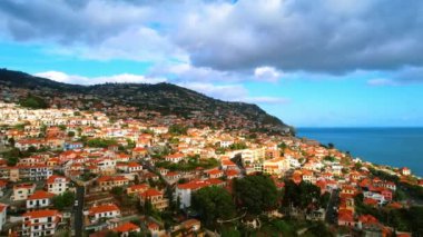 Dağ yamaçları turuncu çatıları olan birçok güzel villa ile inşa edilmiştir. Portekiz, Madeira manzaralarının üzerinde insansız hava aracı görüntüleri.