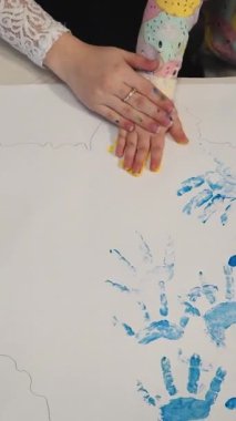 Çocuk kağıt üzerinde el izi yapıyor. Ellerle renkli tasarımlar. Küçük ressam. Dikey video