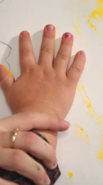 Çocuk kağıt üzerinde el izi yapıyor. Erken çocukluk eğitimi. Küçük ressam. Dikey video